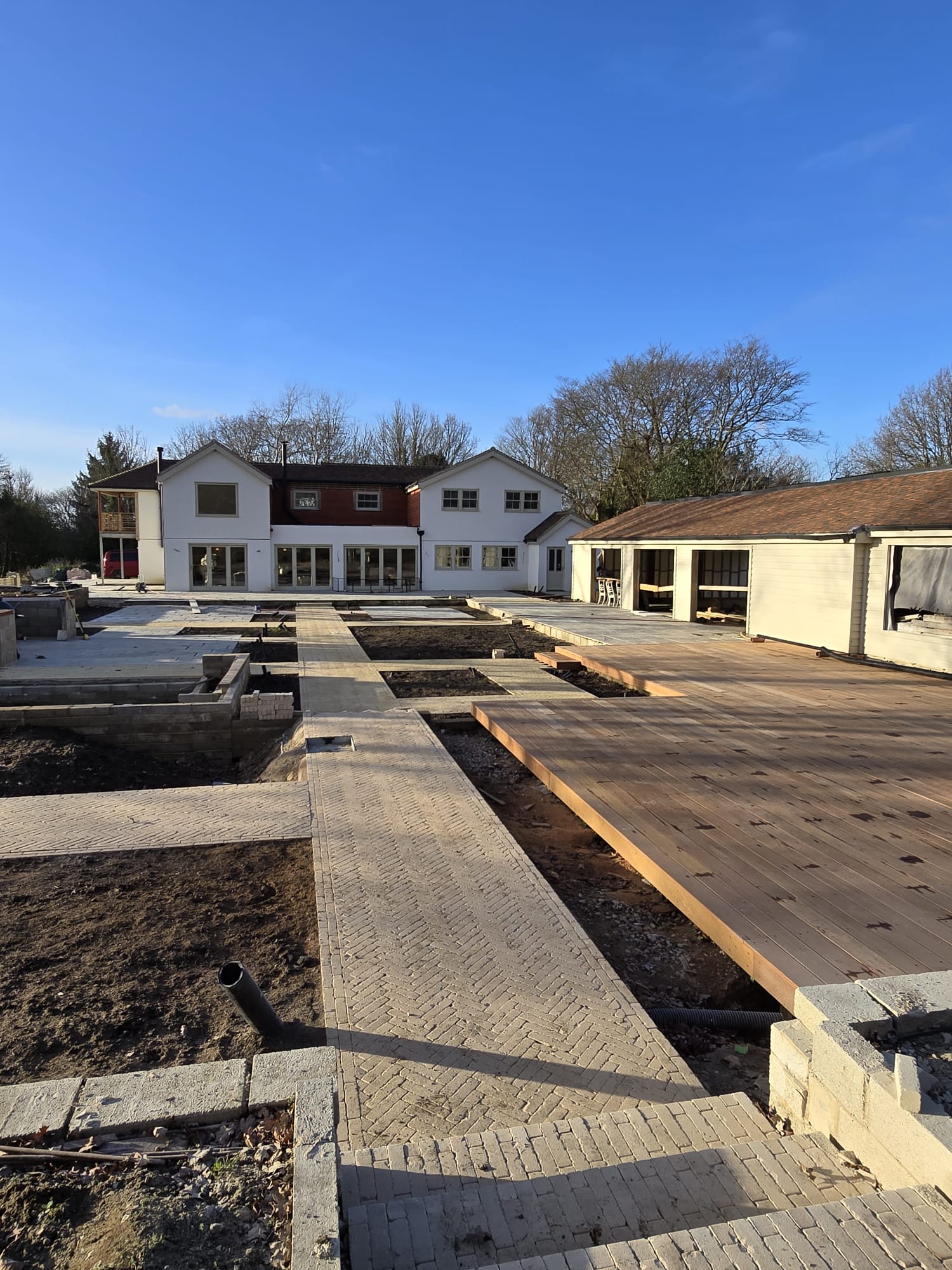 Contemporary lawn with white paving and structured hedging