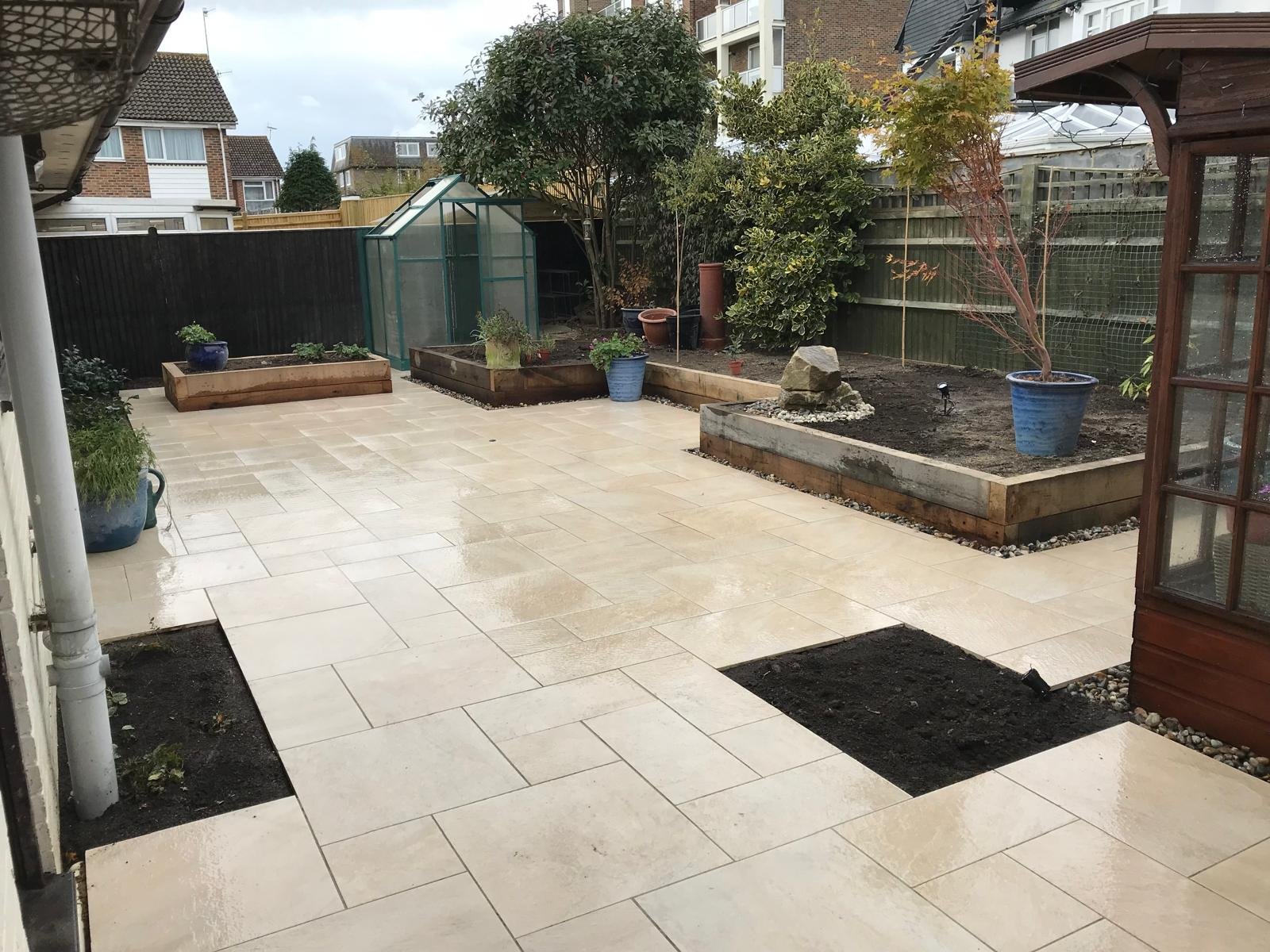 Rear garden with cream stone patio and raised timber beds