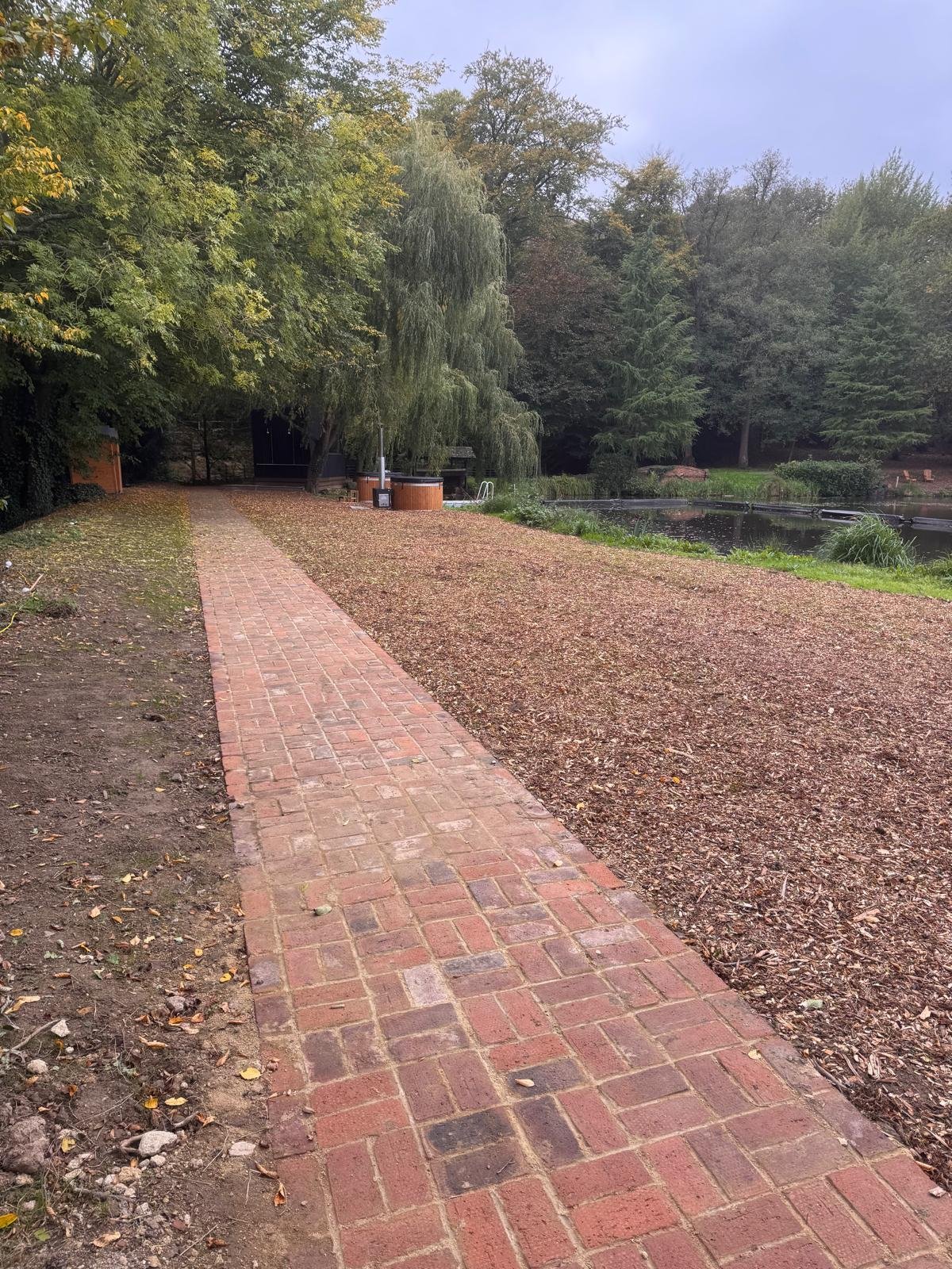 Brick path beside a pond and woodland area